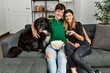 © Krakenimages.com - Young caucasian couple watching movie sitting on the sofa with dog at home.