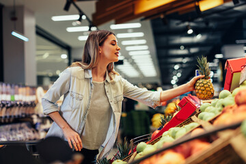 Wall Mural - Young woman buying fruit at the market