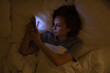 © Eva March - Woman lying on bed using mobile phone  at night, reading or watching, looking at screen. Social addiction, nomophobia. Stress and depression due to insomnia, sleep disorder. Smartphone ruining sleep
