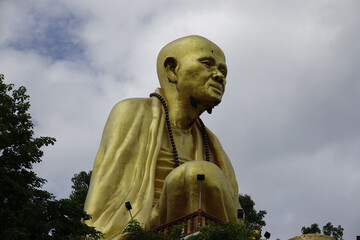 Wall Mural - Old Buddha statue in a rural area in cloudy sky background