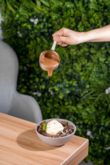 Wall Mural - Selective of a hand pouring chocolate on a bowl of ice cream