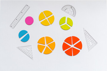 Wall Mural - Background of wooden pie charts. Multicolored math fractions, rulers, pencils on white background. Interesting, fun math for kids. Education, back to school concept