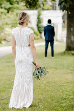 Back Shot Of A Blonde Bride Waiting To Do The First Look With Her Groom In The Garden