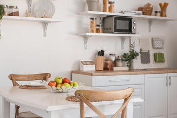 Interior of light kitchen with fruit basket on dining table