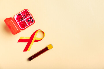 Awareness ribbon with pills and blood sample on beige background. Hepatitis concept