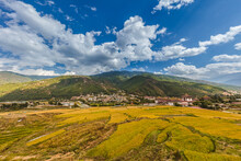 Wide Angle Panorama Over The Free Wild Open Landscape Of Bhutan. The Mountain Of The Himalayas In The Haze On The Horizon. Meadows And Agricultural Land Alternate. The Clouds Climb Over The Mountain