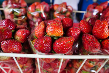 Canvas Print - Closeup shot of fresh red big strawberries arranged in baskets ready for sale at the marketplace