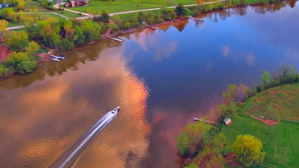 Wall Mural - Aerial view of speed boat tearing across tranquil river's surface reflecting beautiful clouds and sky.
