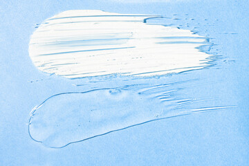 Cream and transparent gel texture samples on a blue background, top view. Skin care, hydration and elasticity maintenance.