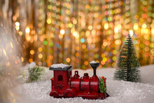 A Holiday Card With A Steam Locomotive In The Snow On A Background With Multicolored Bokeh. Selective Focusing And Shallow Depth Of Field.