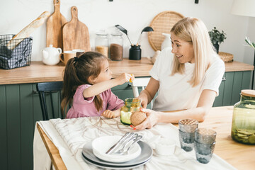 Happy mother and daughter are sitting in the kitchen and hugging.