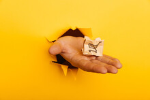 Male Hand With A Small Broken Delivery Box Through A Yellow Paper Hole. Delivery Service Mistake