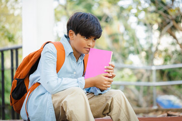 portrait of confident student boy sitting staircase outdoors on campus at the school