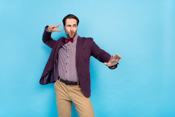 Sticker - Photo of young excited man look empty space clubber show fingers v-symbol isolated over blue color background