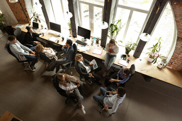 Young people talking, working with colleagues, co-workers at loft style office. Business, urban lifestyle, work, finance, tech concept. Aerial view