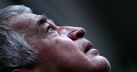 Older man in crisis looking at sky with hope and faith