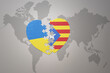 puzzle heart with the national flag of ukraine and catalonia on a world map background. Concept.