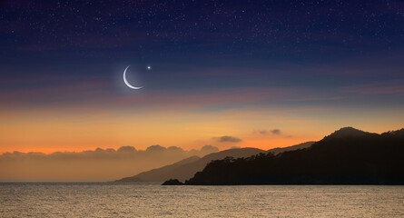 Wall Mural - Ramadan background with crescent, stars in glowing sky above mountains and sea.