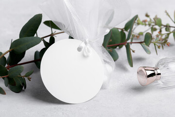 Wall Mural - Round white gift tag mockup with eucalyptus leaves on grey background, label tag mockup, Wedding favor tag for souvenir, sign for greeting message close up, element for design