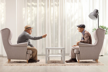 Wall Mural - Pensioners sitting in armchairs and talking in a living room