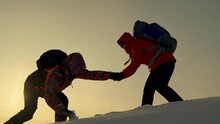 Traveler Climbs Snowy Peak, Working In Team Of Business People. Silhouettes Of Climbers Give Each Other Helping Hand, Climbing To Top Of Snowy Mountain, Hill. Team Of Businessmen Is Going To Win.