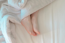 Children's Feet Under A White Blanket. The Tenderness Of Morning Sleep.