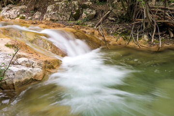 Wall Mural - Cascade of waterfalls among stones. Fluffy water. Spring landscape. Falling water.