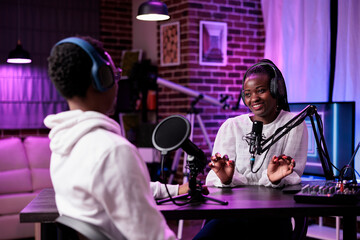 Wall Mural - African american man and woman recording live podcast in studio, using sound production equipment. Happy influencers meeting to create social media content on internet broadcast.