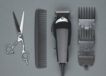 Scissors, Comb, Hair Clipper. Professional Barber Hair Clipper And Shears For Man Haircut. Hairdresser Salon Equipment. Premium Hairdressing Accessories. Top View Flat Lay On Gray Background