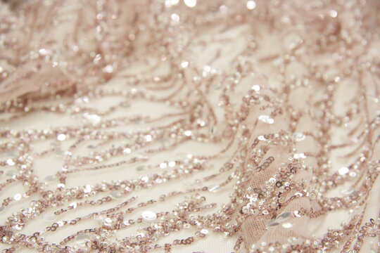 Pink decorated fabric. Intricate beaded and sequined ornaments. Bokeh effect, defocused. Natural shimmering