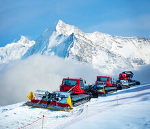 Group Of Snow Groomers Over Alps Mountain Summits