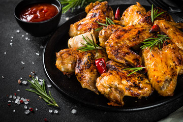 Grilled chicken wings with spices in black plate.