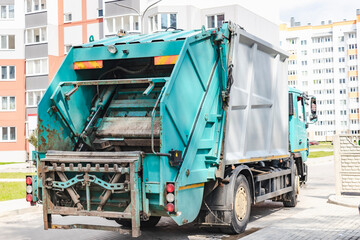 Fototapete - A garbage truck picks up garbage in a residential area. Loading mussar in containers into the car. Separate collection and disposal of garbage. Garbage collection vehicle.