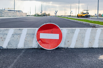 A stop road sign and concrete blocks block the entrance to the construction site. Closed road. Construction and road works.