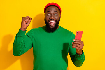 Wall Mural - Portrait of attractive lucky cheerful guy using gadget rejoicing like post smm isolated over bright yellow color background