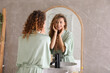 © New Africa - Beautiful woman looking at herself in bathroom mirror