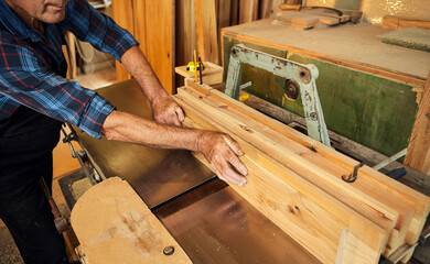 Wall Mural - Senior carpenter in uniform works on a woodworking machine at the carpentry manufacturing