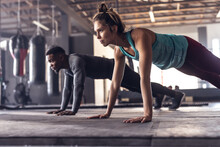 Multiracial Dedicated Young Male And Female Athletes Doing Pushups On Floor In Health Club