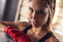 Close-up Portrait Of Determined Confident Caucasian Young Female Boxer Wearing Red Boxing Wraps