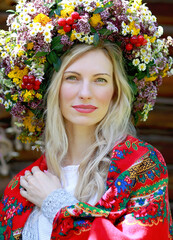 Wall Mural - a beautiful blonde girl with a smile in a flower wreath, a red scarf on her shoulders. Independence Day. Embroidery day. Glory to Ukraine! Ukrainian traditions concept