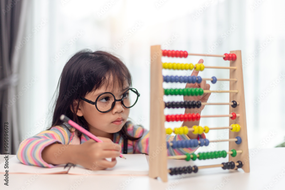 A young cute Asian girl is using the abacus with colored beads to learn ...