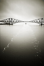 Forth Bridge With Container Ships Wake - In Black And White Toned Image.