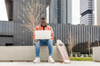 © ADDICTIVE STOCK - Young black guy using netbook on bench in park