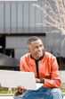 © ADDICTIVE STOCK - Young black guy using netbook on bench in park