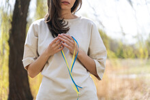 Lady With Blue And Yellow Ribbons In Hands Standing In Nature