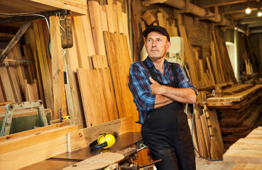 Wall Mural - Portrait of Senior carpenter in uniform works on a woodworking machine at the carpentry manufacturing