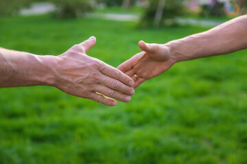 Handshake of men at a meeting in the park. Selective focus.