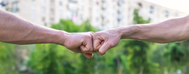 Fists of men at a meeting in the park. Selective focus.