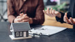 © Puwasit Inyavileart - Real estate agent or sales manager has offered home sales and explained the terms of signing the house purchase contract and free home insurance, Finance and after-sales service concept.