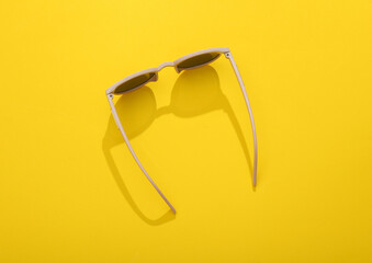 Sticker - Top view stylish sunglasses on yellow bright background.